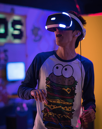 A guy with a funny burger t-shirt wears a virtual reality headset and is amazed by the virtual worlds he dives into.